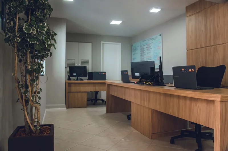 Espacio de oficina contemporáneo con escritorios, ordenadores y sillas giratorias.